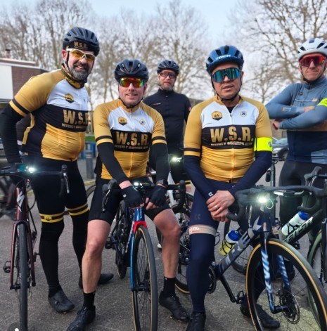 WSR-rijders in clubkleding met hun racefietsen, klaar voor vertrek